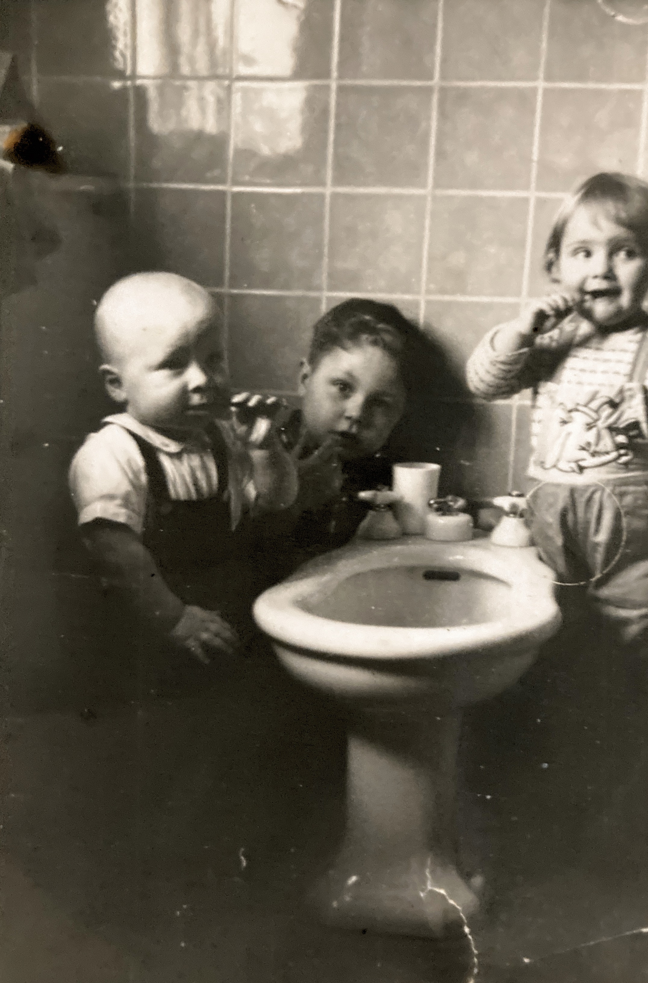 Vernon, Billy, and Chantal brushing teeth from bidet. France. 1954 