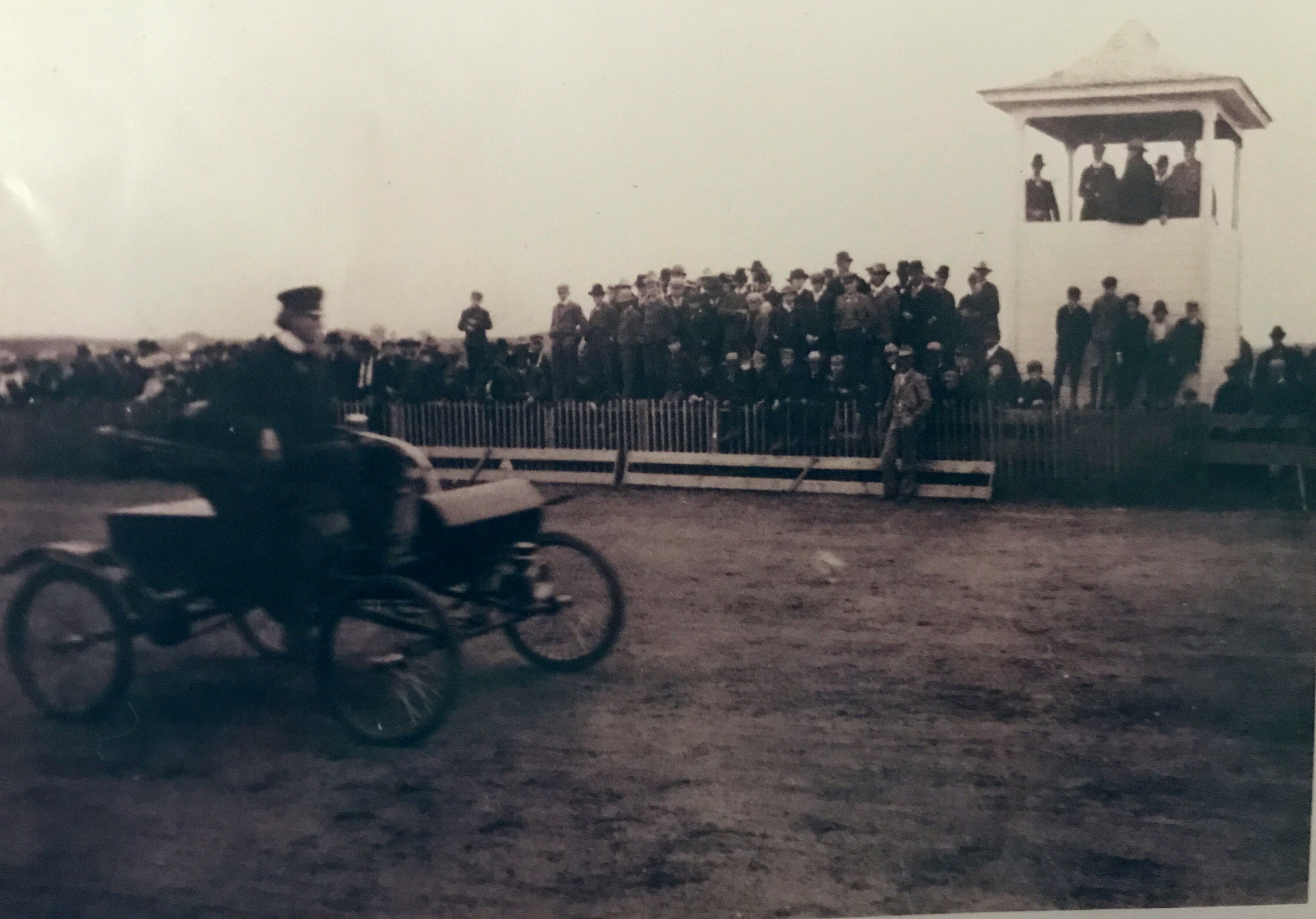 September 1902. Grandpa Fred C. Shardlow demonstrating his first car, an Oldsmobile, at county fair at Hutchison, MN. Car was purchased in November 1901. 